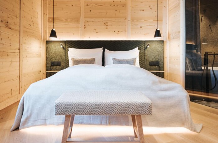 Stilfuldt soveværelse med træ, naturlige materialer og moderne alpint design på Hotel Schneider i Obertauern