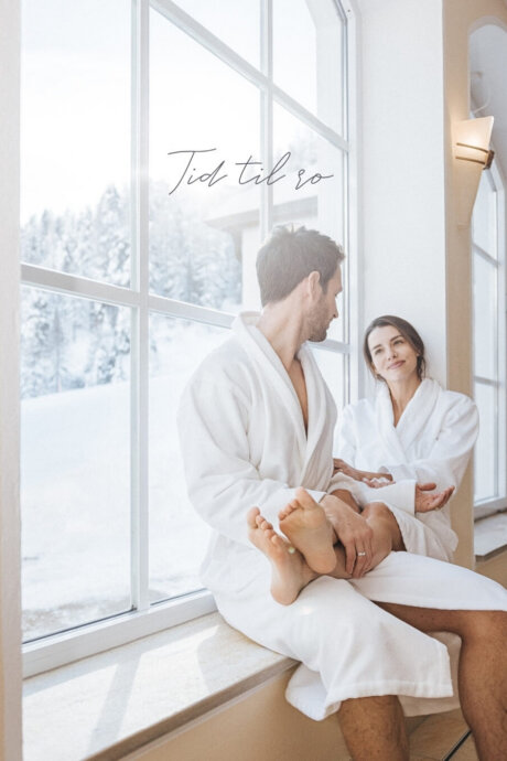 Par nyder afslapning i spaområdet på Hotel Schneider med udsigt til de sneklædte bjerge i Obertauern