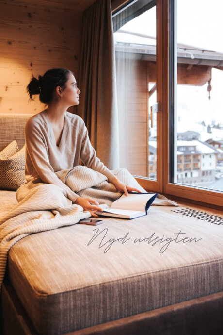 Gæst nyder udsigten over Obertauern fra et stilfuldt værelse med naturlige materialer på Hotel Schneider