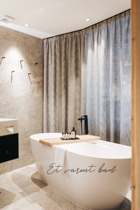 Moderne badeværelse med badekar på Hotel Schneider i Obertauern. Perfekt til afslapning efter en aktiv dag i sneen.