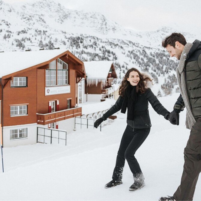 Par nyder sneen foran Hotel Schneider i det snesikre Obertauern omgivet af de østrigske Alper