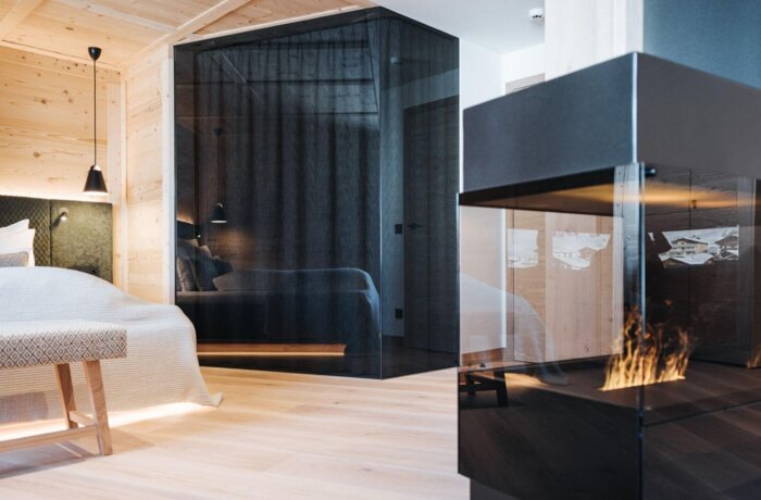 Elegant designsuite med pejs, soveområde og naturlige materialer på Hotel Schneider i Obertauern