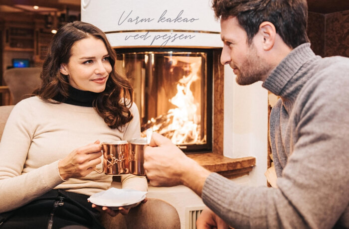 Par nyder varm chokolade ved pejsen i den hyggelige lounge på Hotel Schneider i Obertauern