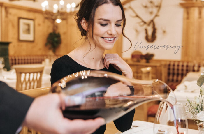 Gæst nyder et glas vin til middag i restauranten på Hotel Schneider i Obertauern
